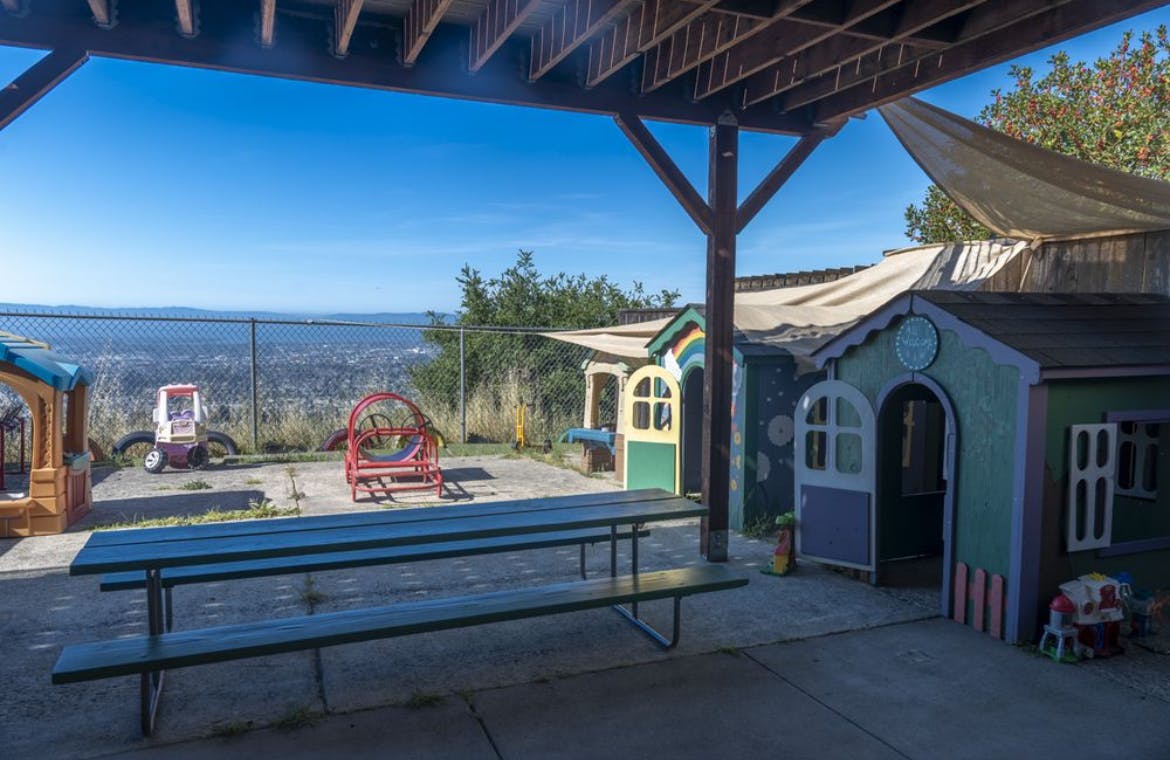 Playhouses and playground equipment on a patio overlooking a hillside view