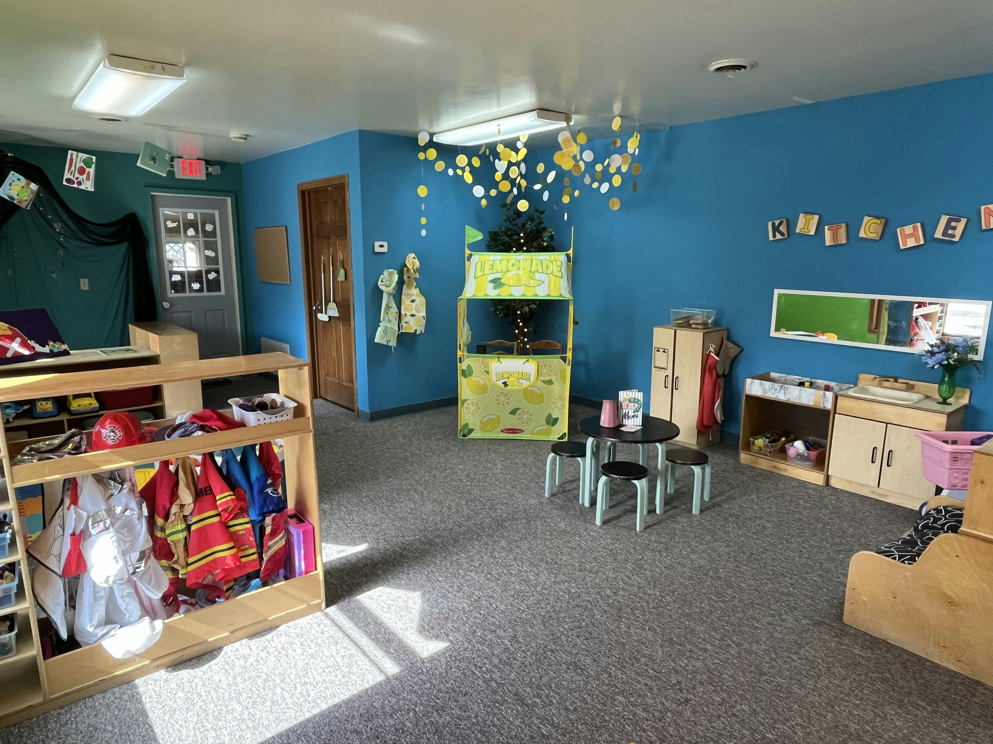 Playroom with blue walls, dress-up clothes, and small tables and chairs