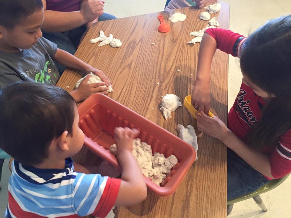 Children playing with dough at a table