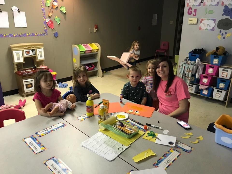 Adult and children sitting at a table with craft supplies