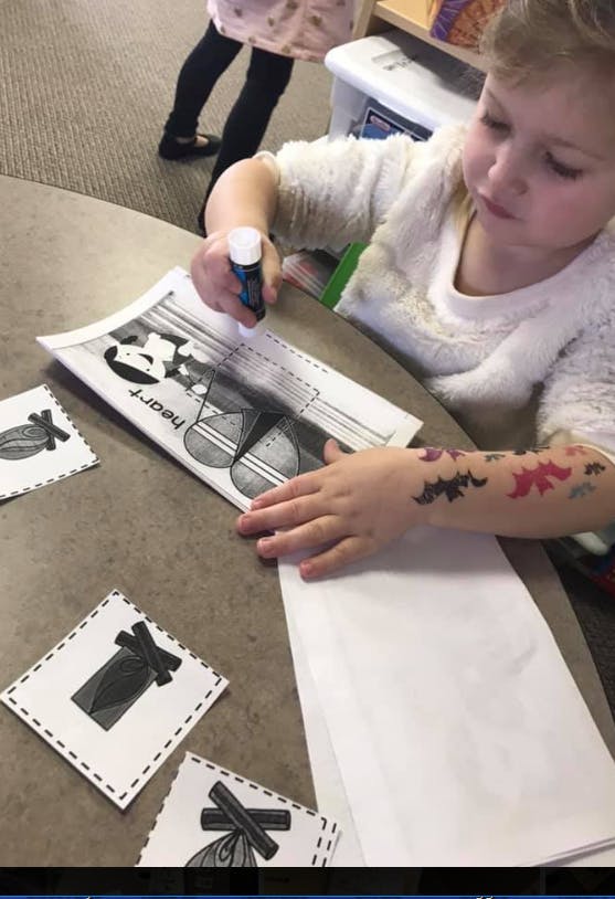 Child using a glue stick on a paper craft
