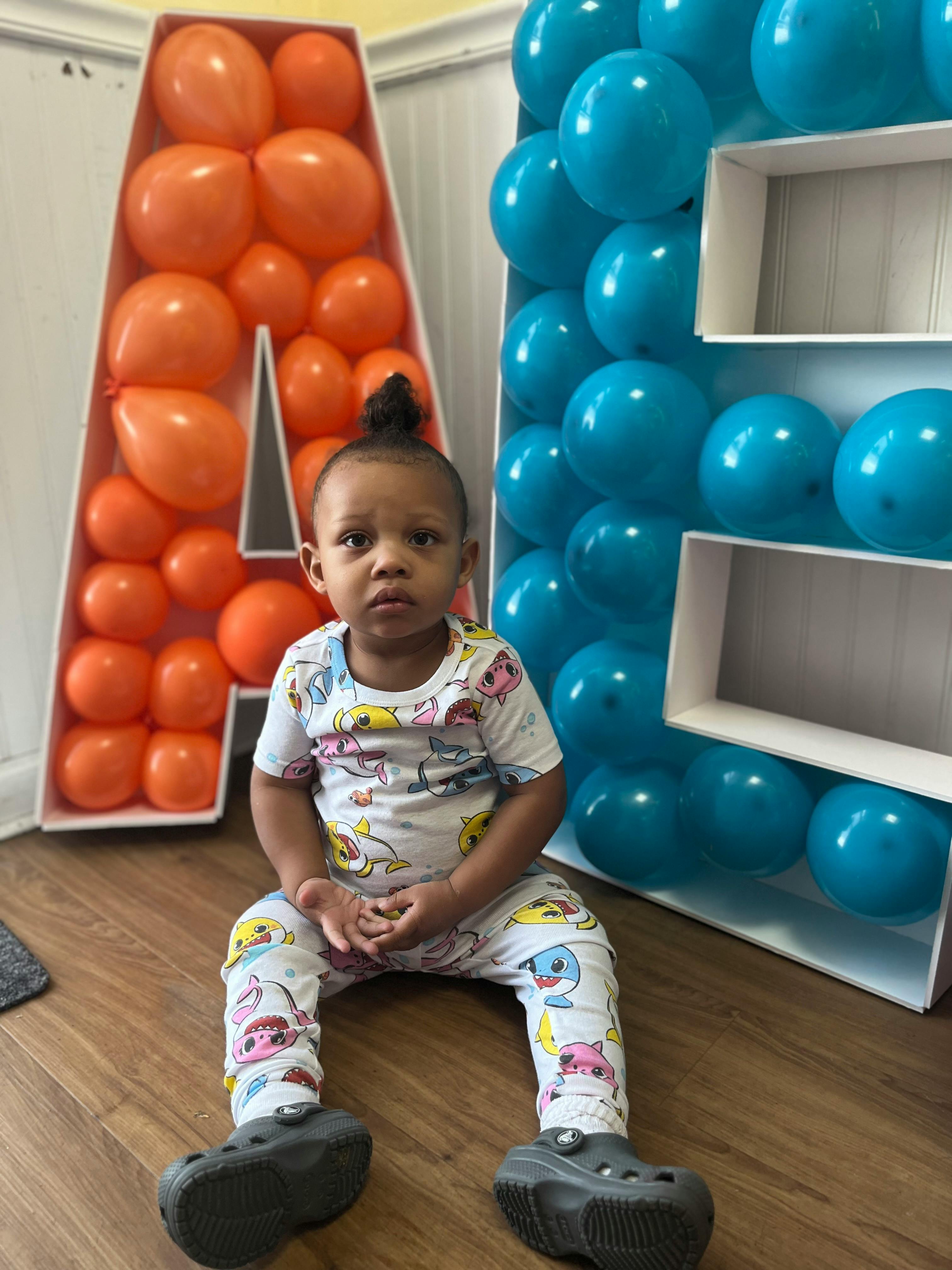 Child sitting on floor in front of balloon decorations