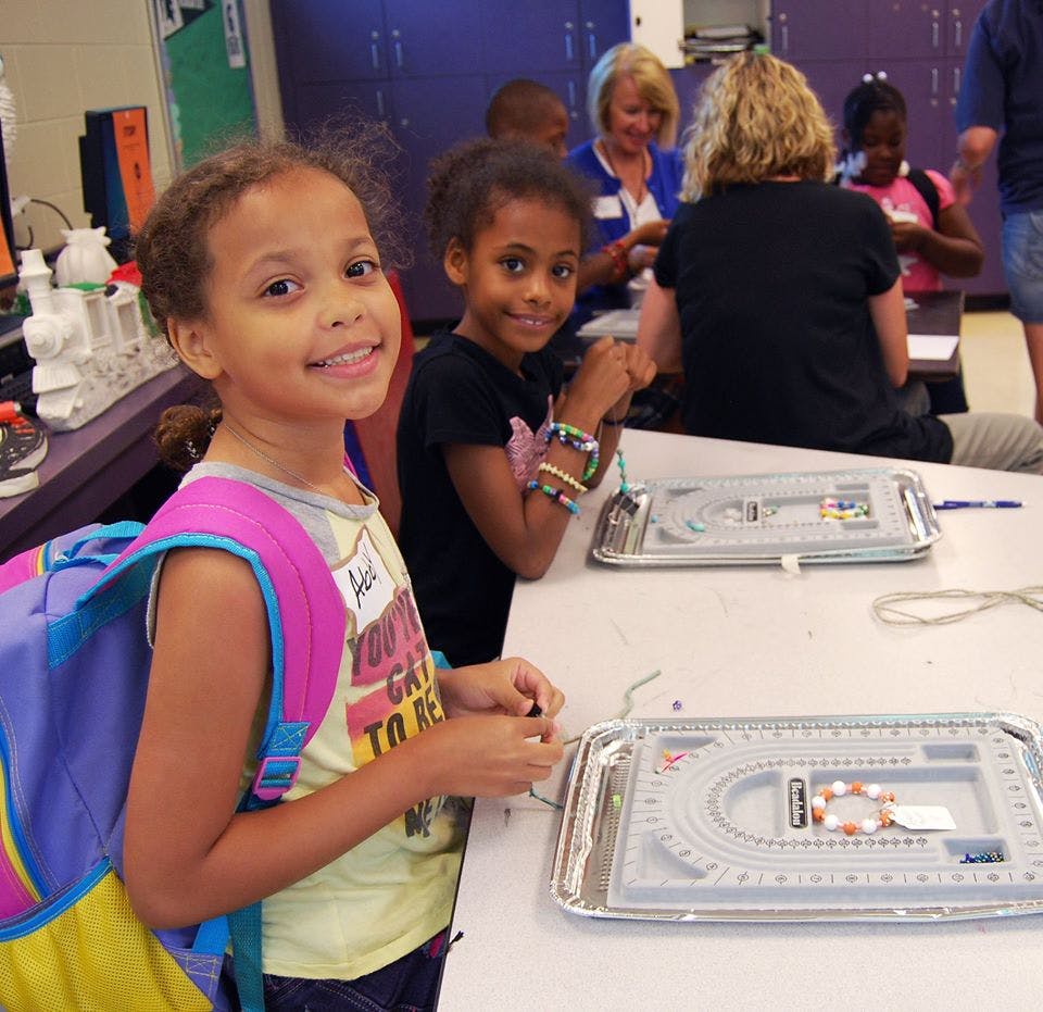 Two children making bracelets at a table