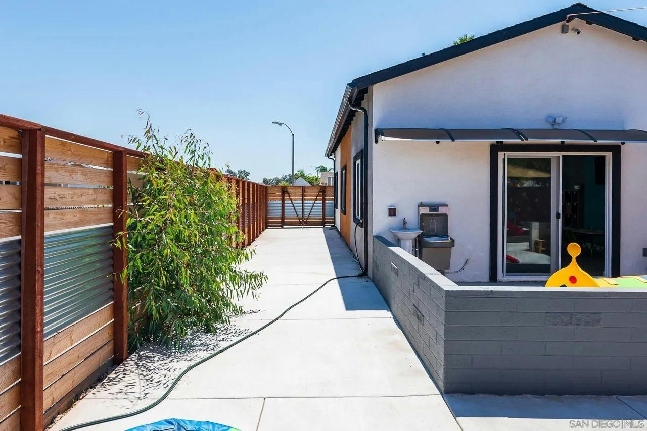 Concrete side yard with a wooden fence and a wall by the house