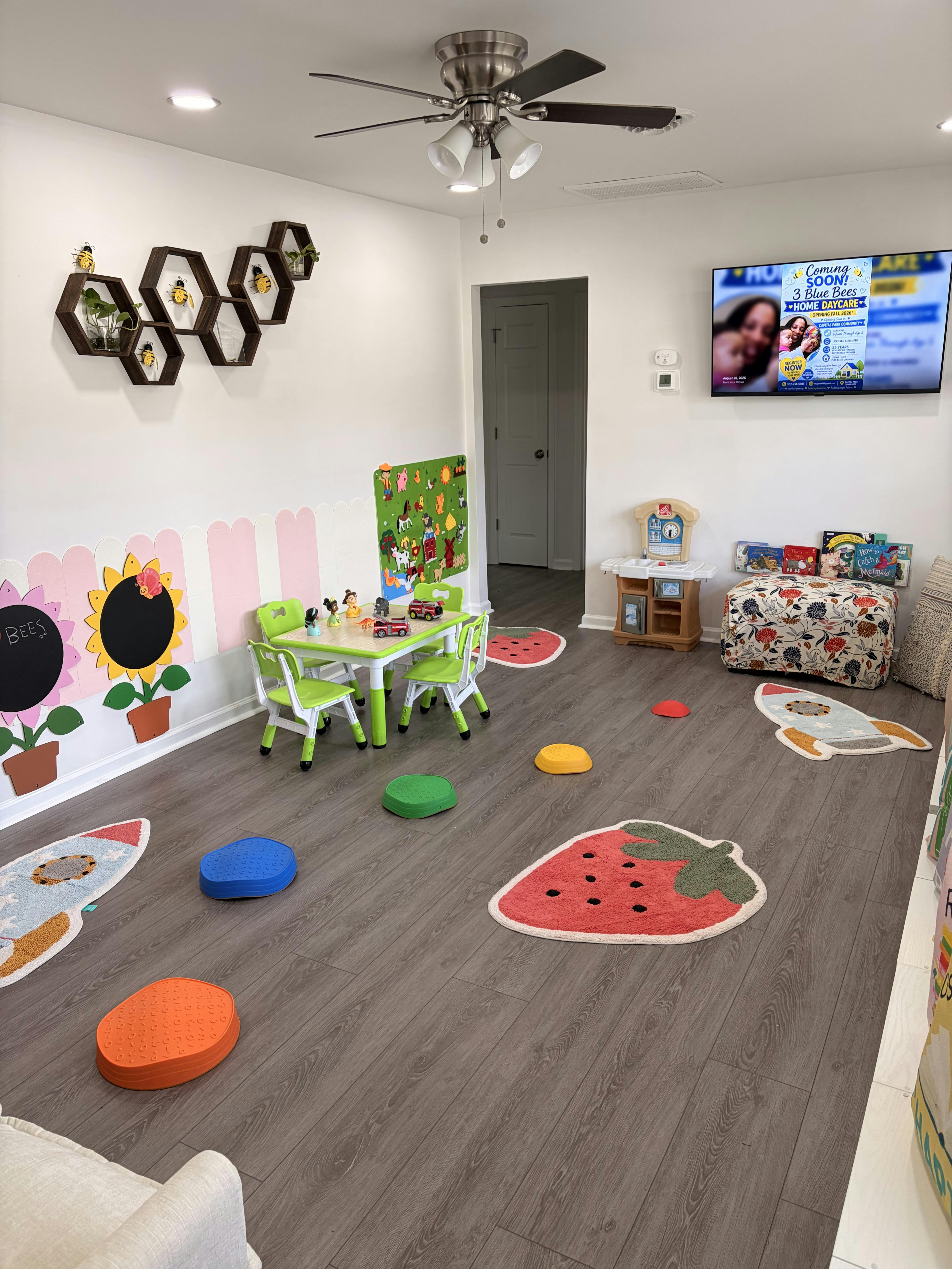Childcare room with a small table, chairs, and colorful play mats on the floor