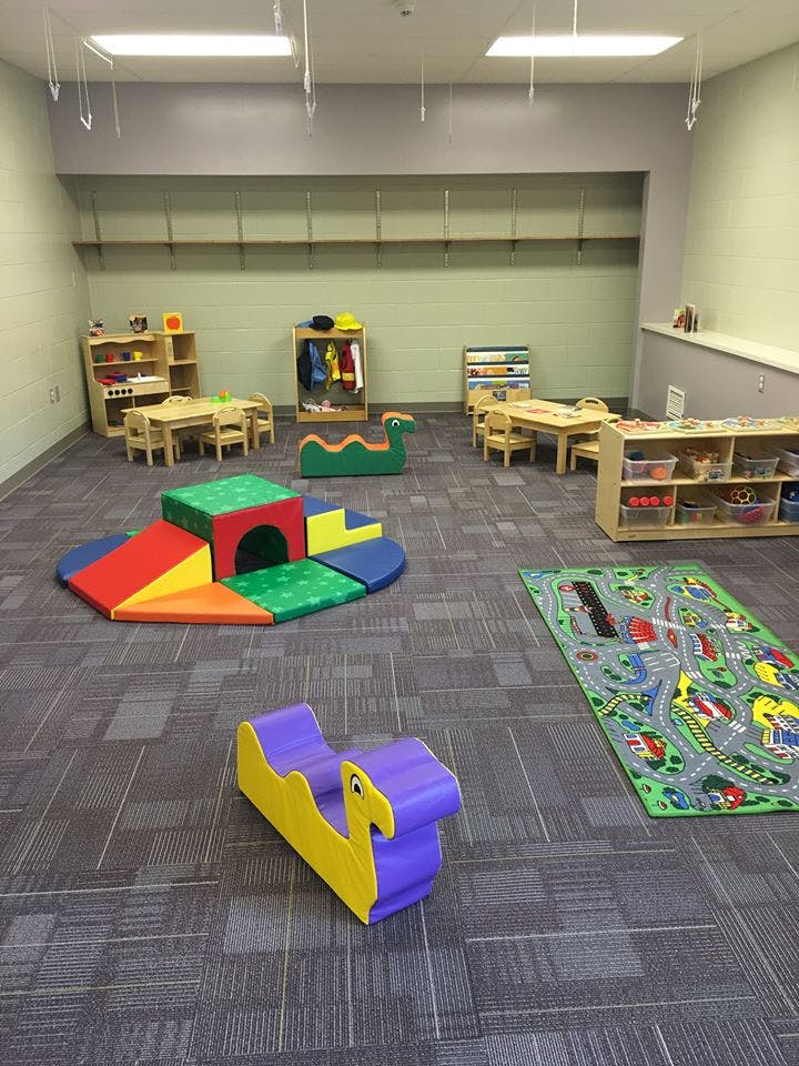 Playroom with soft play equipment, small tables and chairs, and a road map rug