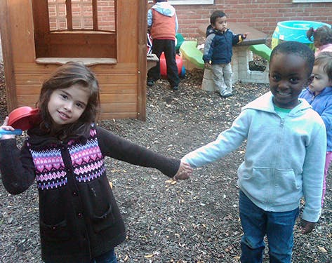 Two children holding hands on a playground
