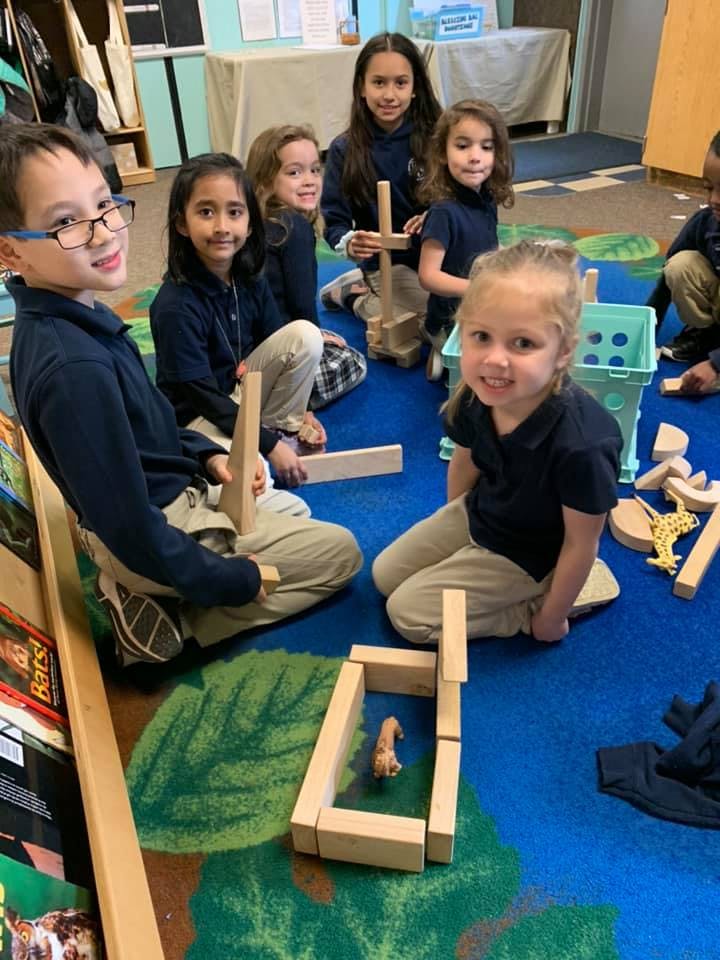 Children playing with wooden blocks on a blue rug