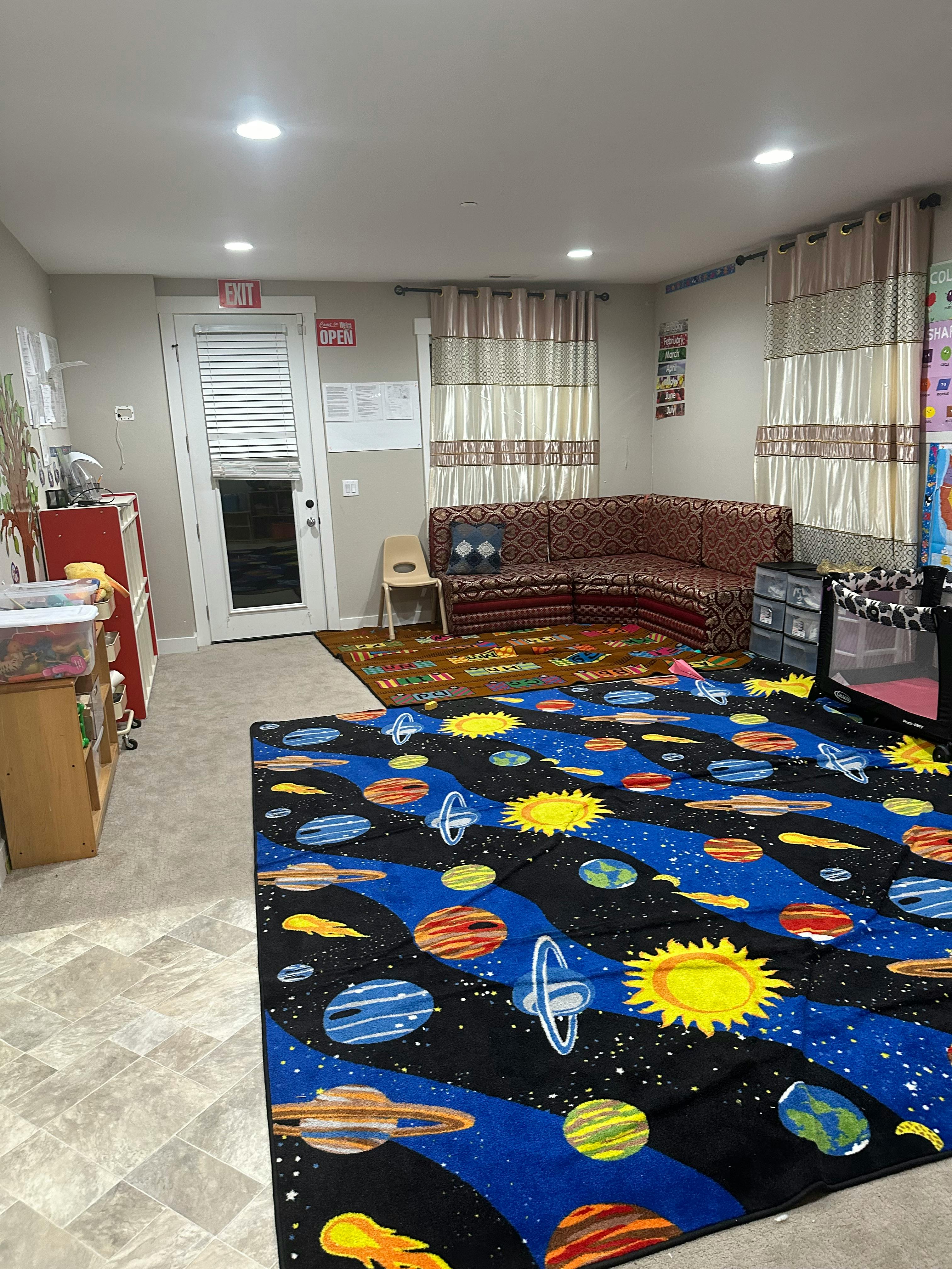 Room with a space-themed rug, a sofa, and a door
