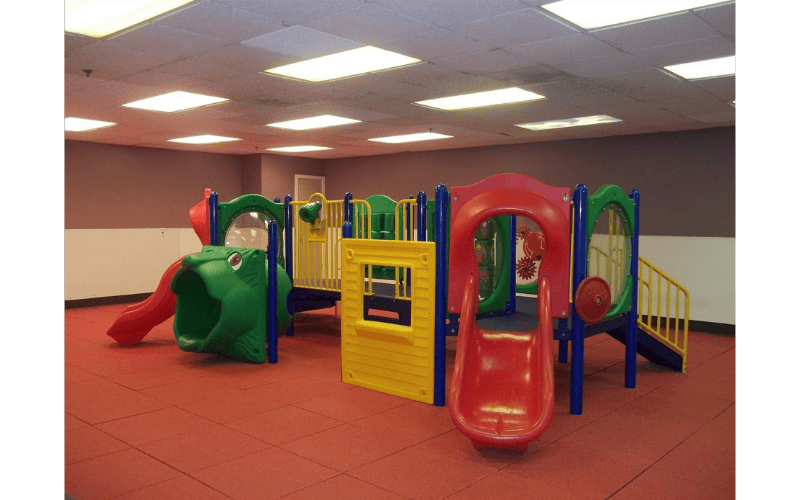 Colorful indoor playground with red slides and green, yellow, and blue structures