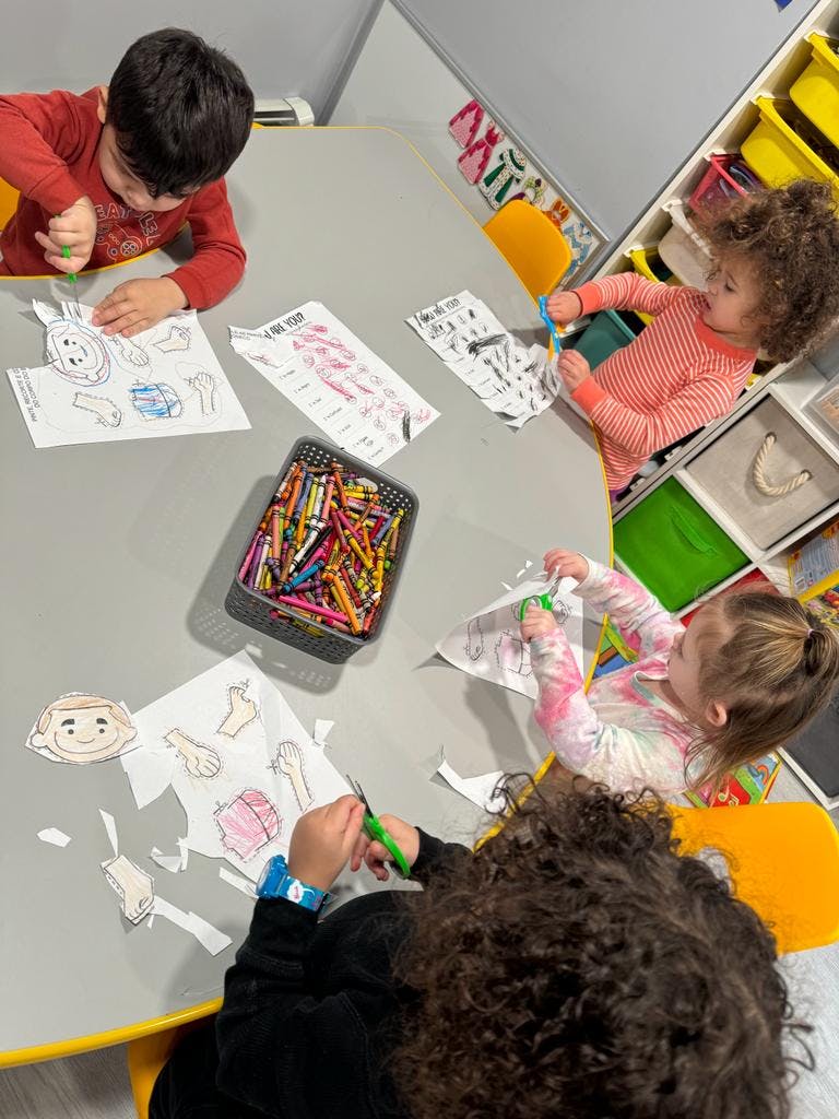 Children cutting and coloring paper at a table