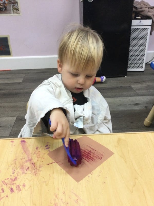 Child painting with a roller on a piece of paper