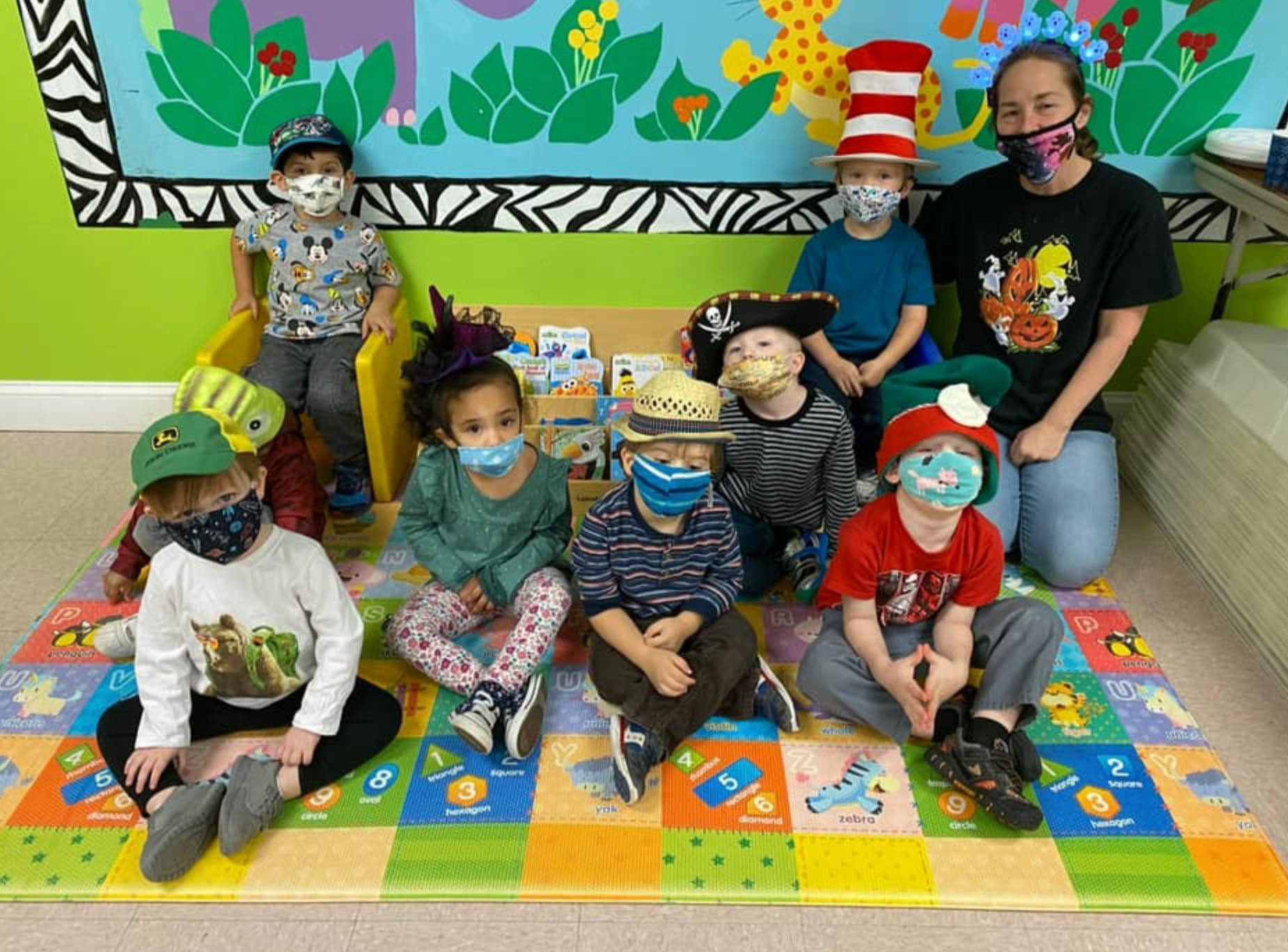 Adult and children wearing masks and costumes sitting on a colorful mat