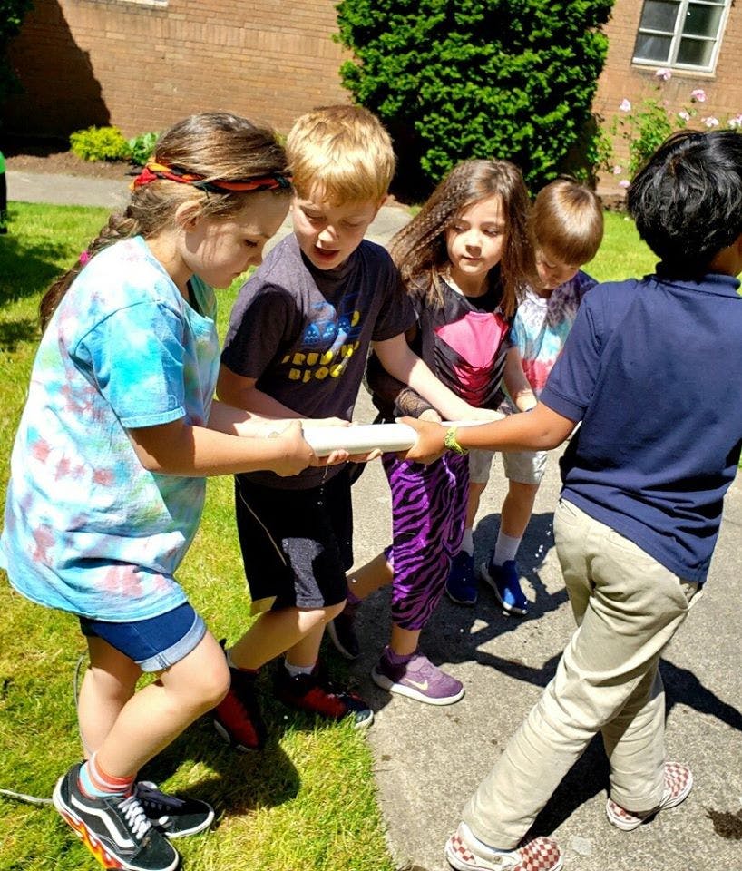 Children holding a long, narrow object together