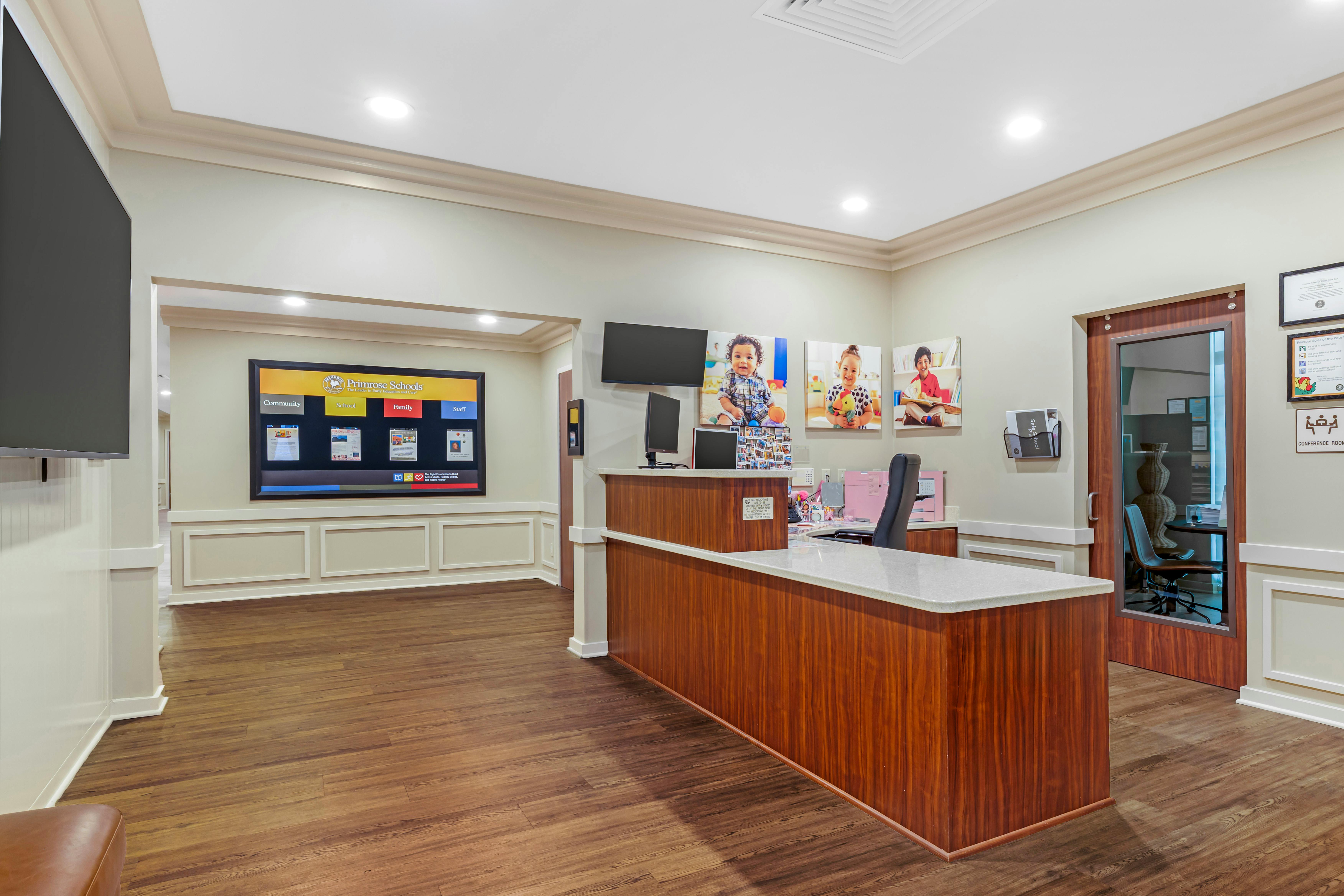 Primrose Schools reception area with a wooden desk and screens on the walls