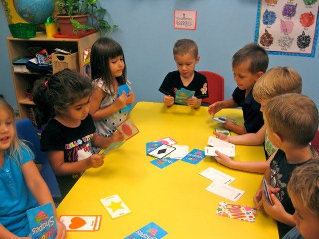 Children playing a card game at a yellow table