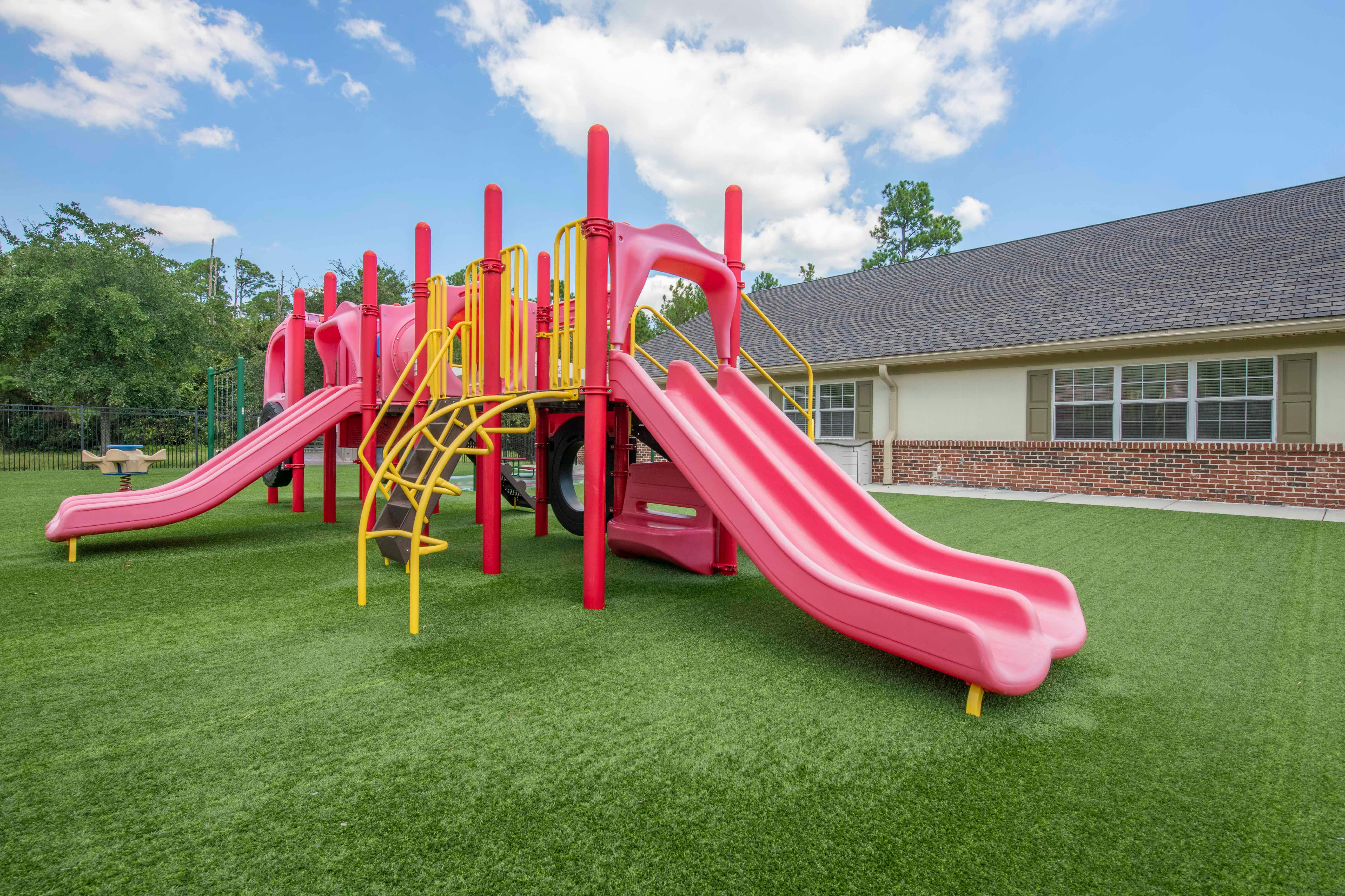 A red and yellow playground on green artificial turf