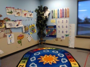 Classroom corner with children's artwork and a sun rug