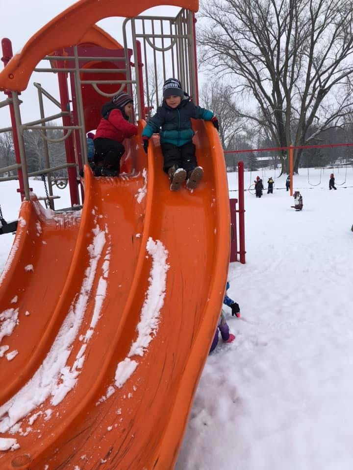 Children playing on a snow-covered playground slide