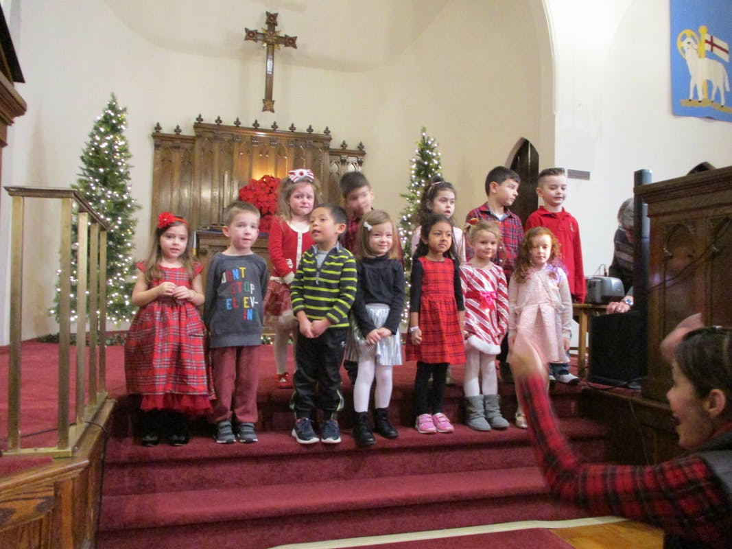 Group of children standing on steps in front of a cross