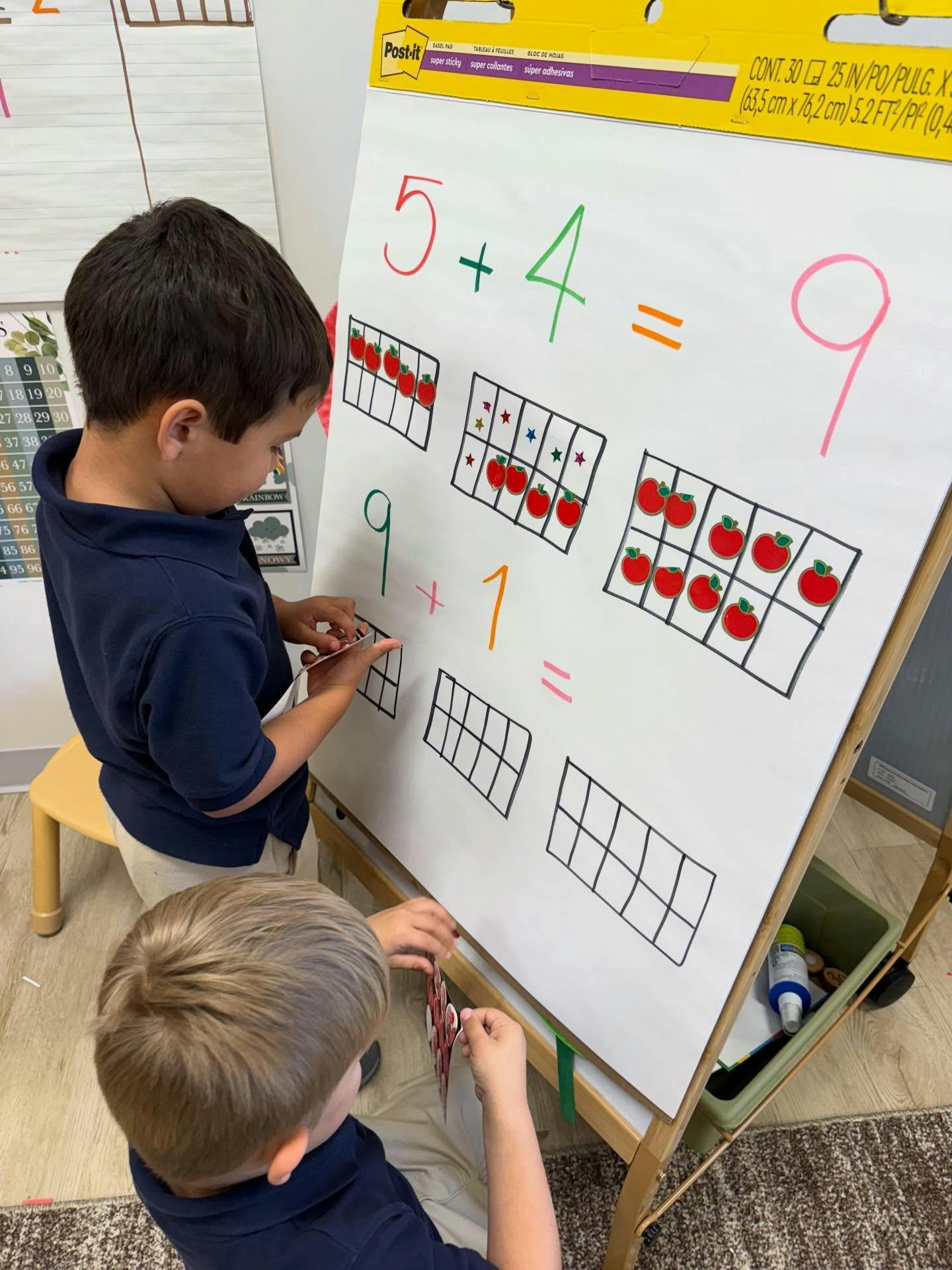Children working on math equations with stickers on a classroom easel pad