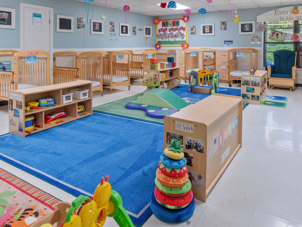 An empty nursery room with cribs, play mats, and toys