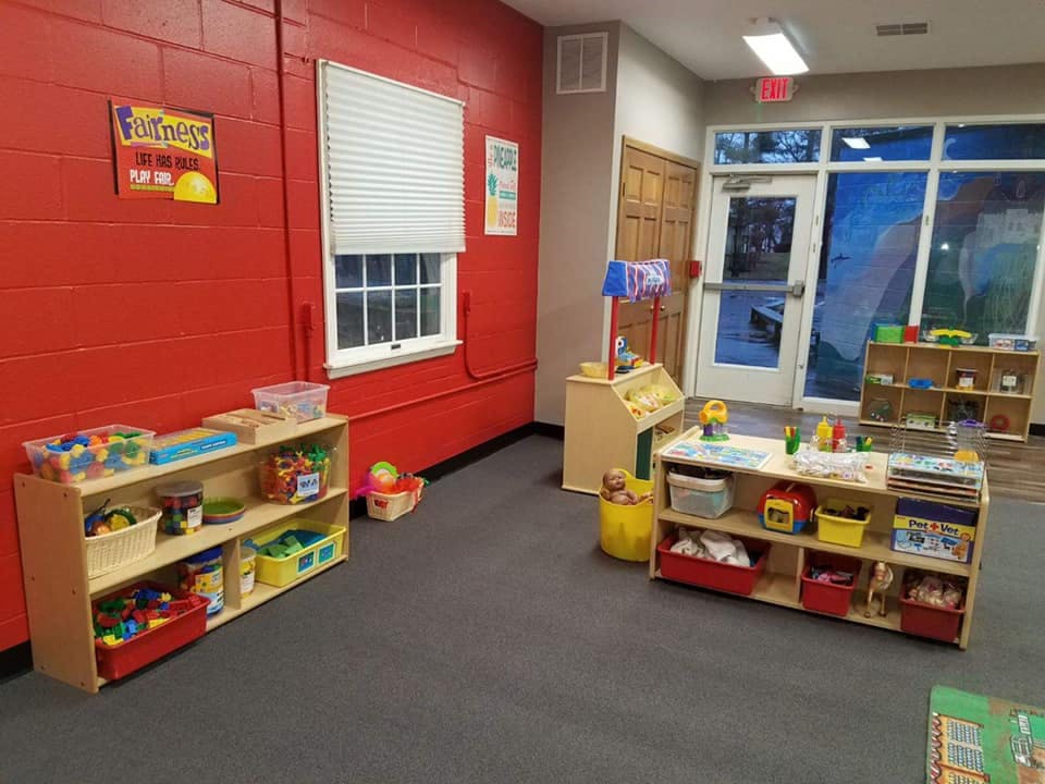 Classroom with red walls, window, and shelves with toys