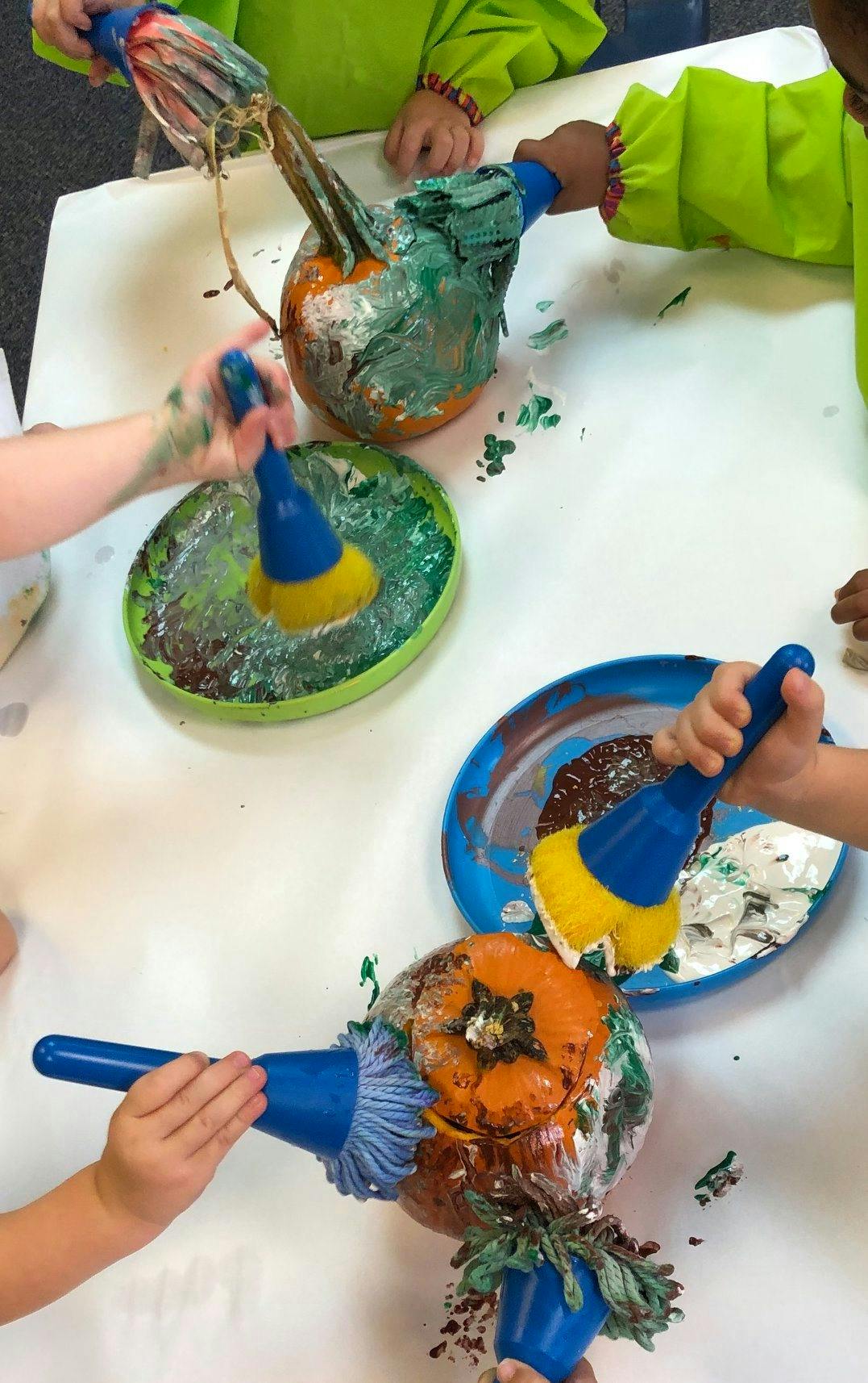 Children painting pumpkins with brushes