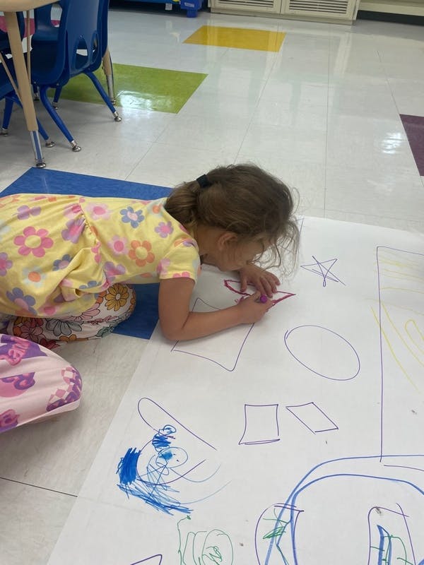 Child drawing on large paper on the floor