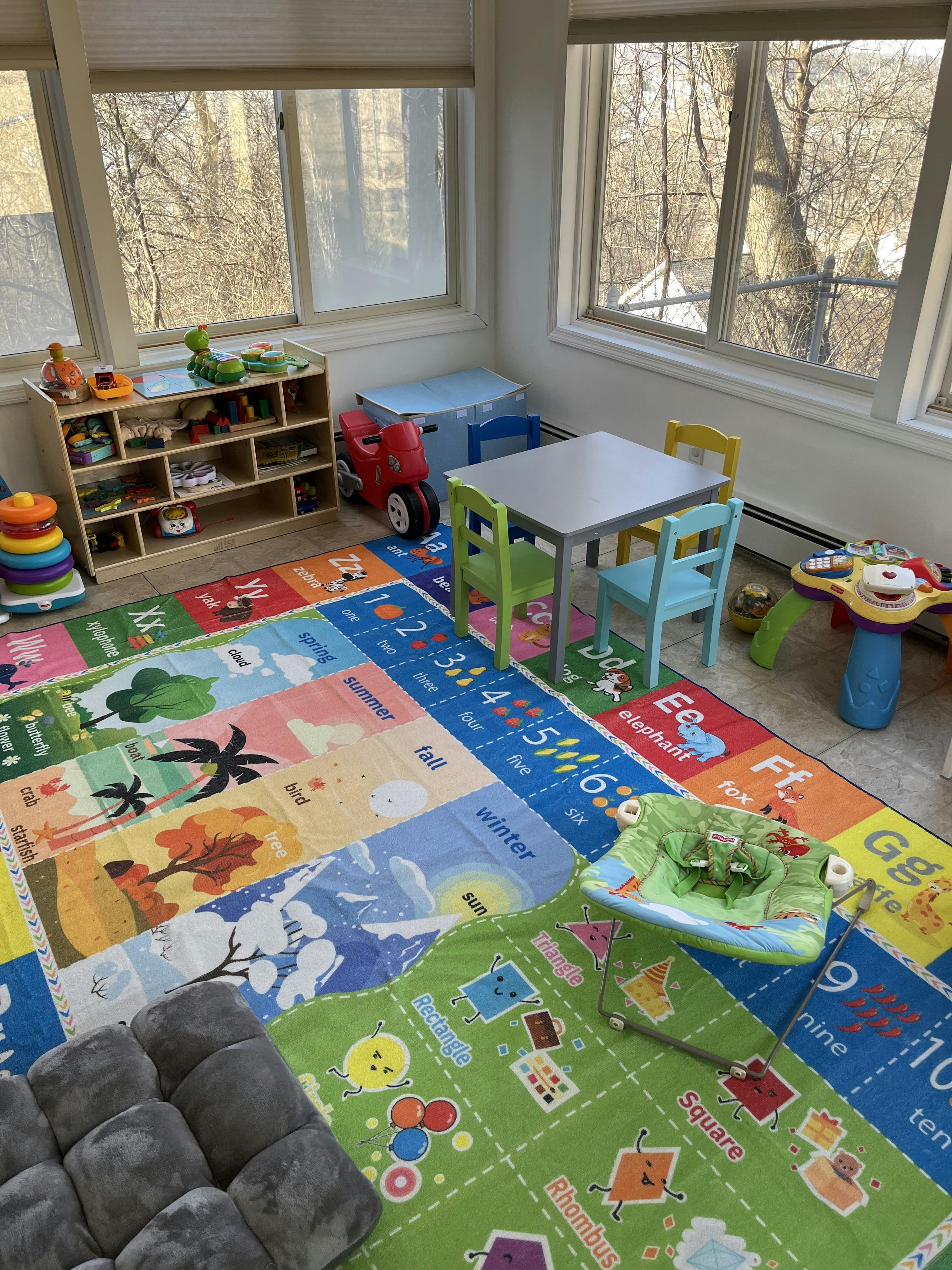 Playroom with colorful alphabet and number rugs, small table and chairs, and toys