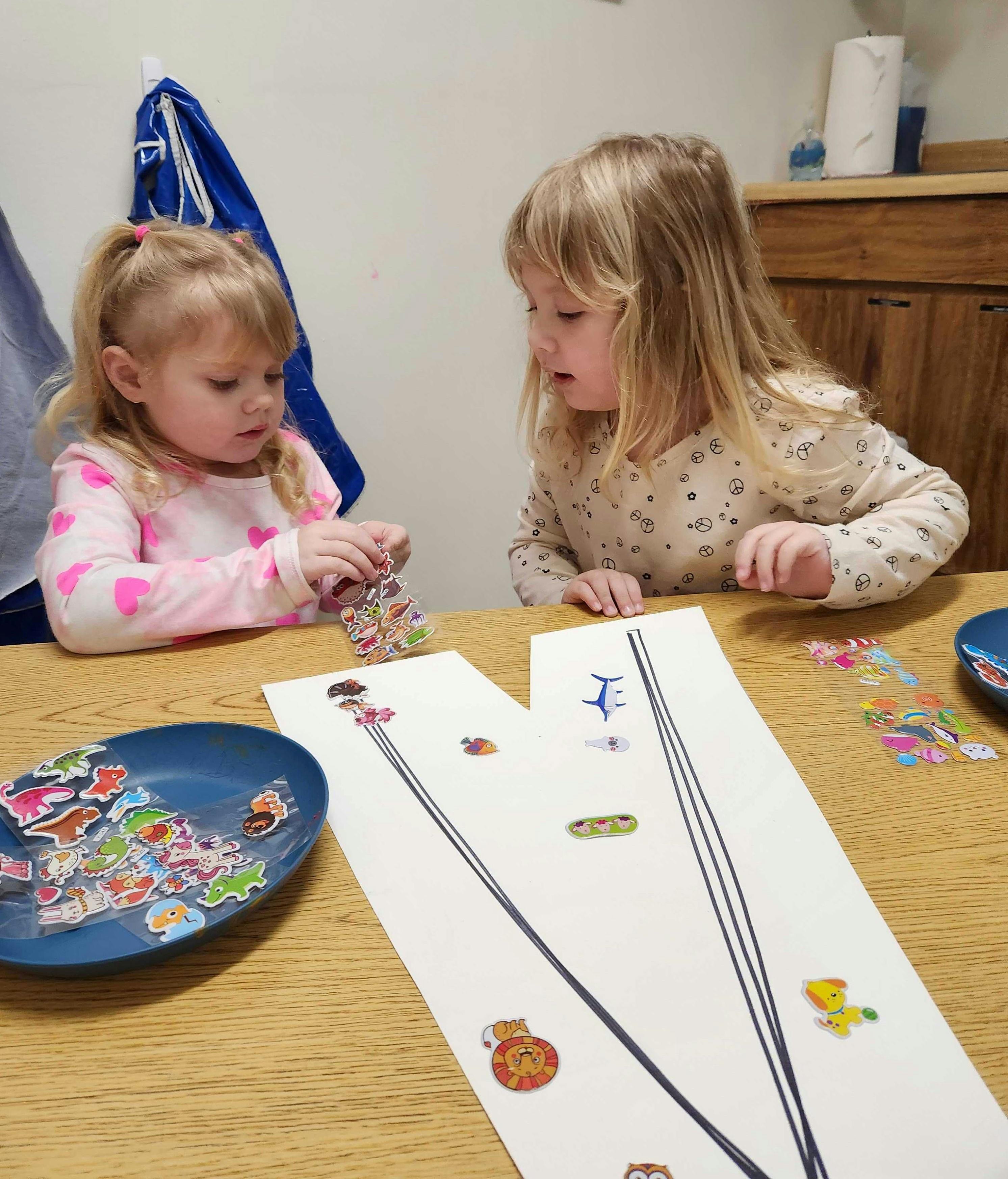 Two children playing with stickers at a table