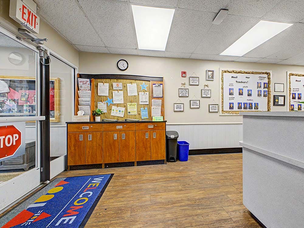 Lobby area with a bulletin board, wooden cabinets, and a "WELCOME" mat