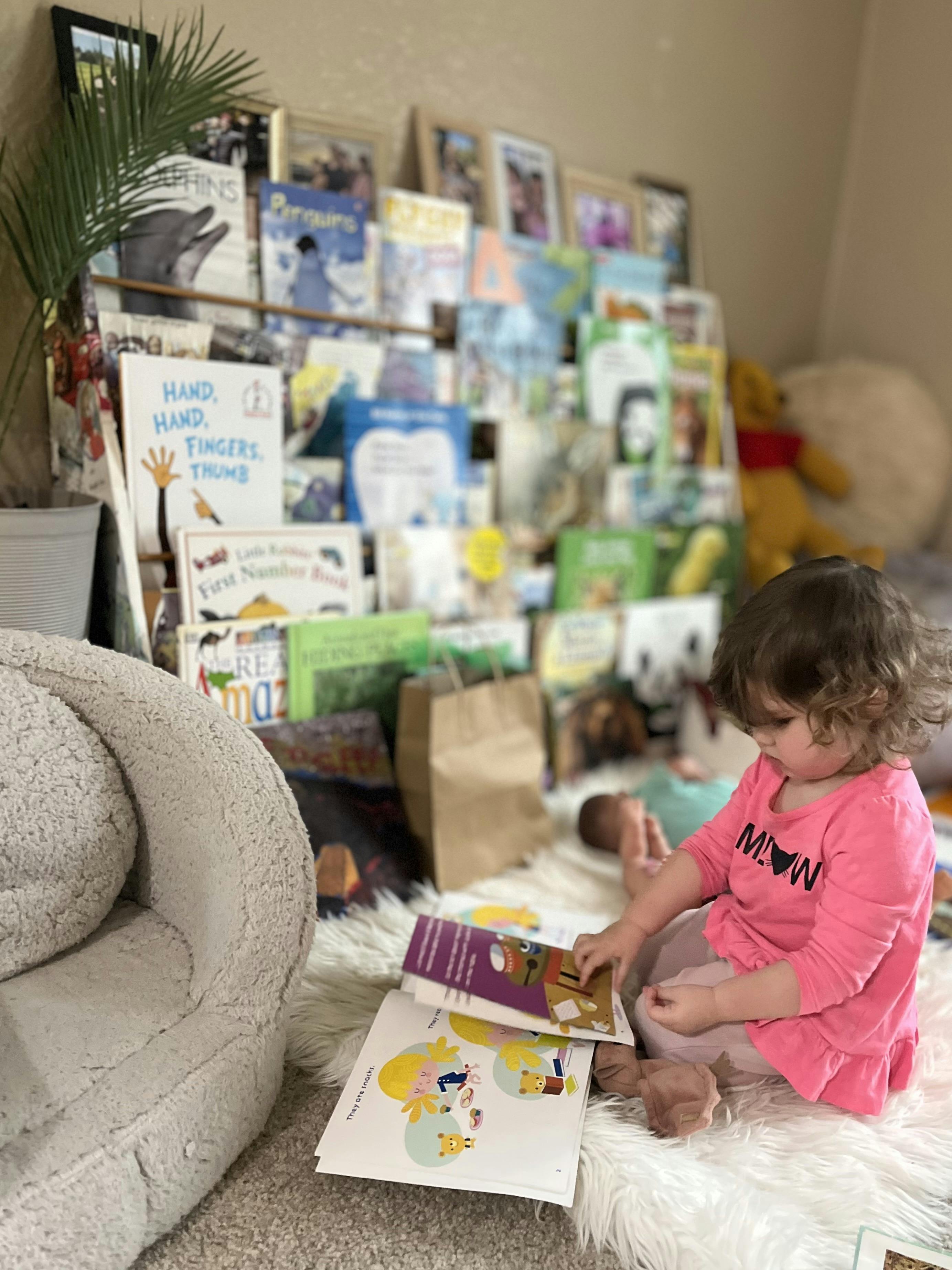 Child sitting on a rug reading a book in front of a bookshelf