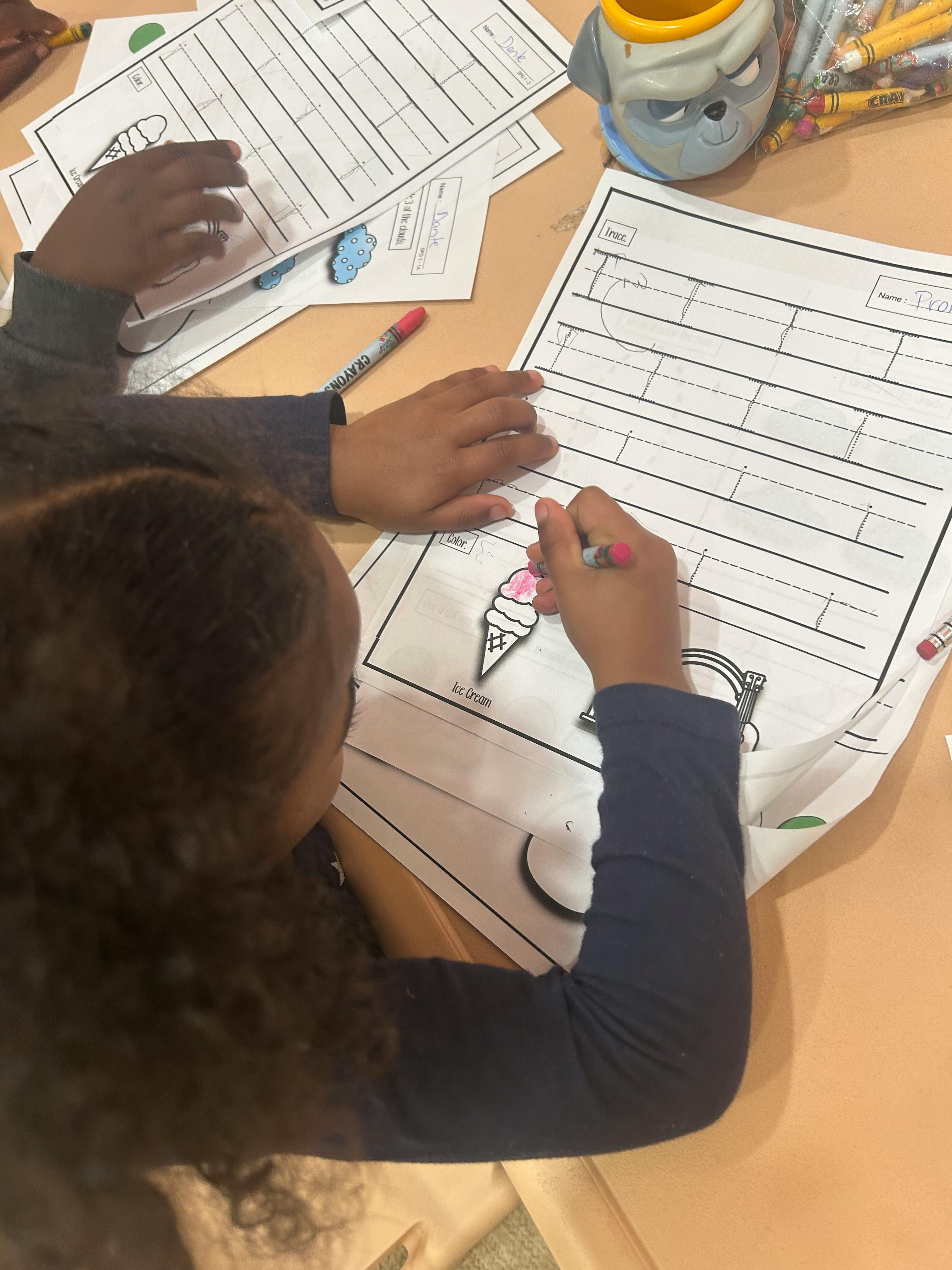 Child coloring an ice cream cone on a worksheet
