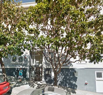 Building entrance with trees and parked cars