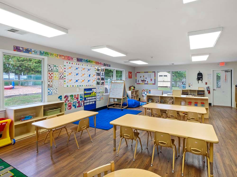 Empty colorful preschool classroom with small tables and chairs