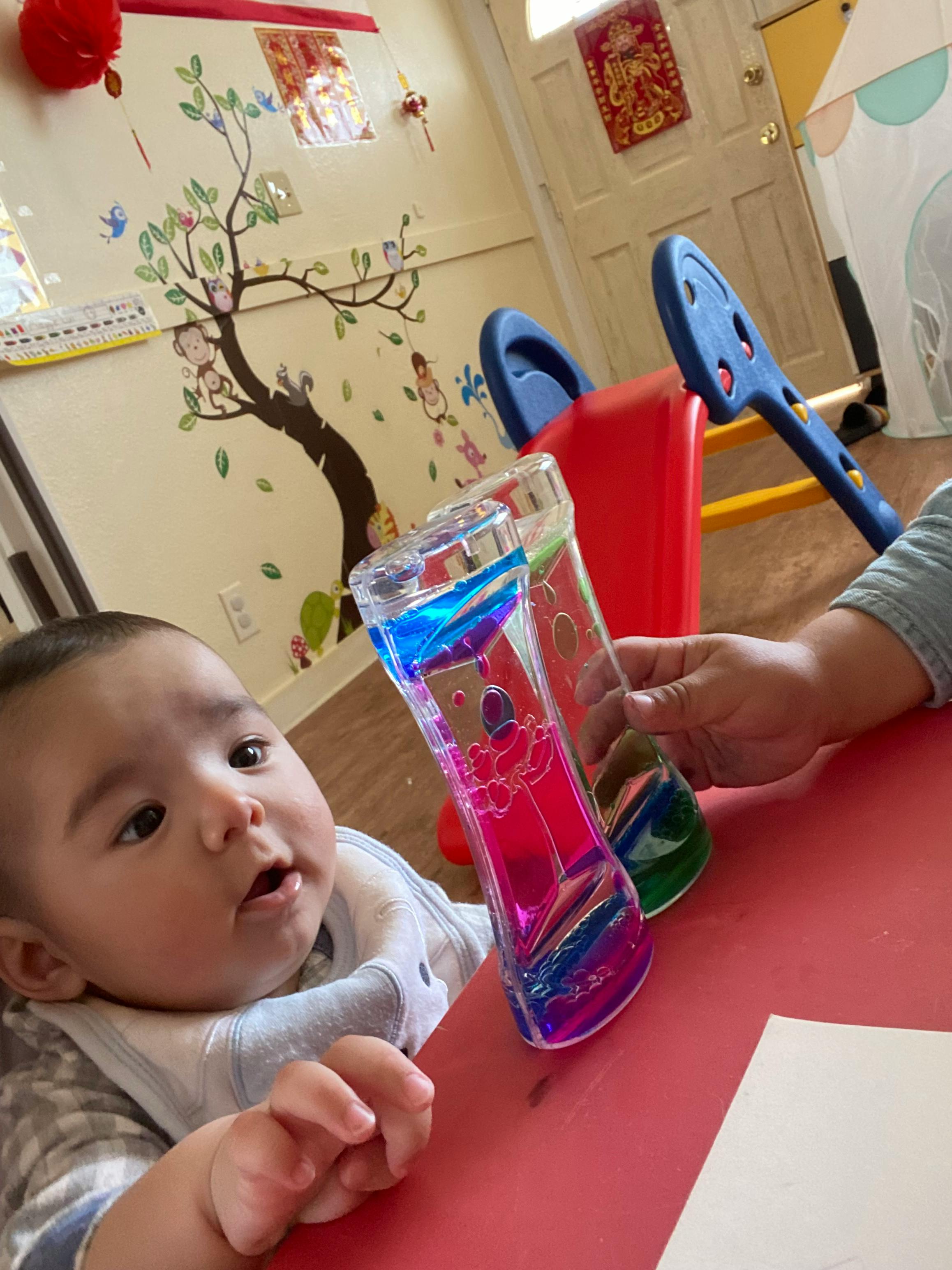 Child looking at a colorful liquid timer held by a person