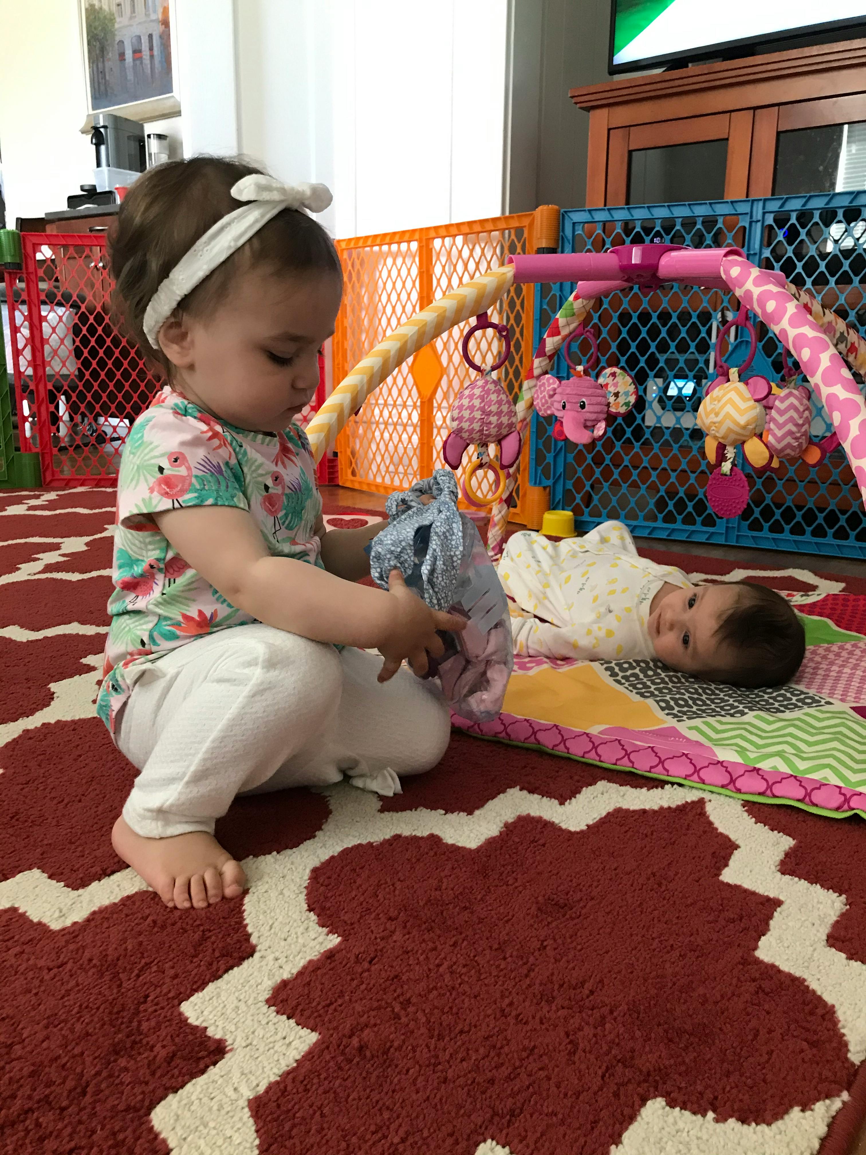 Child playing with a toy while another child lies on a mat