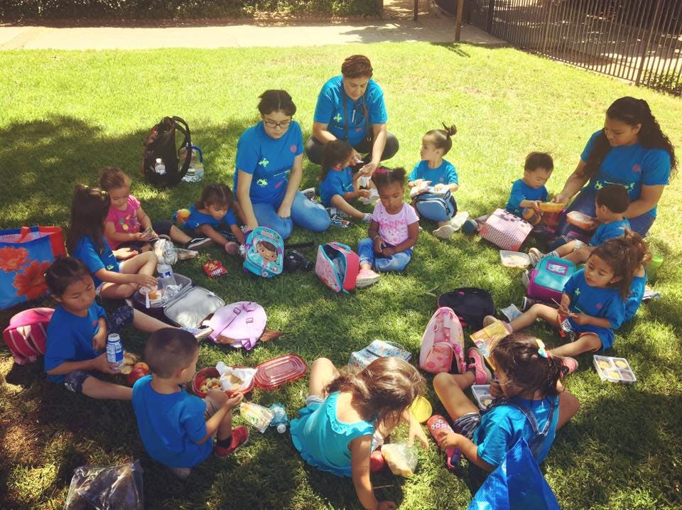 Adults and children sitting in a circle on grass