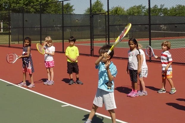 Children on a tennis court holding rackets
