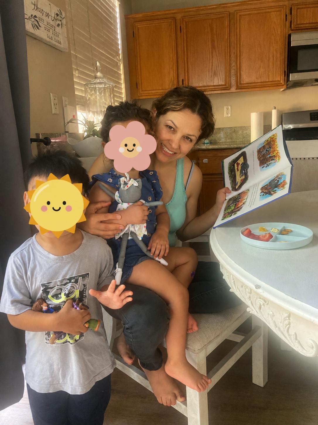 Person holding a child on their lap while reading a book, another child stands nearby