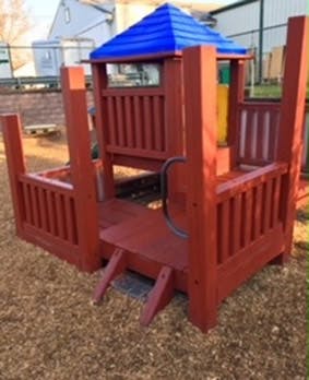 Red wooden playground structure with blue roof
