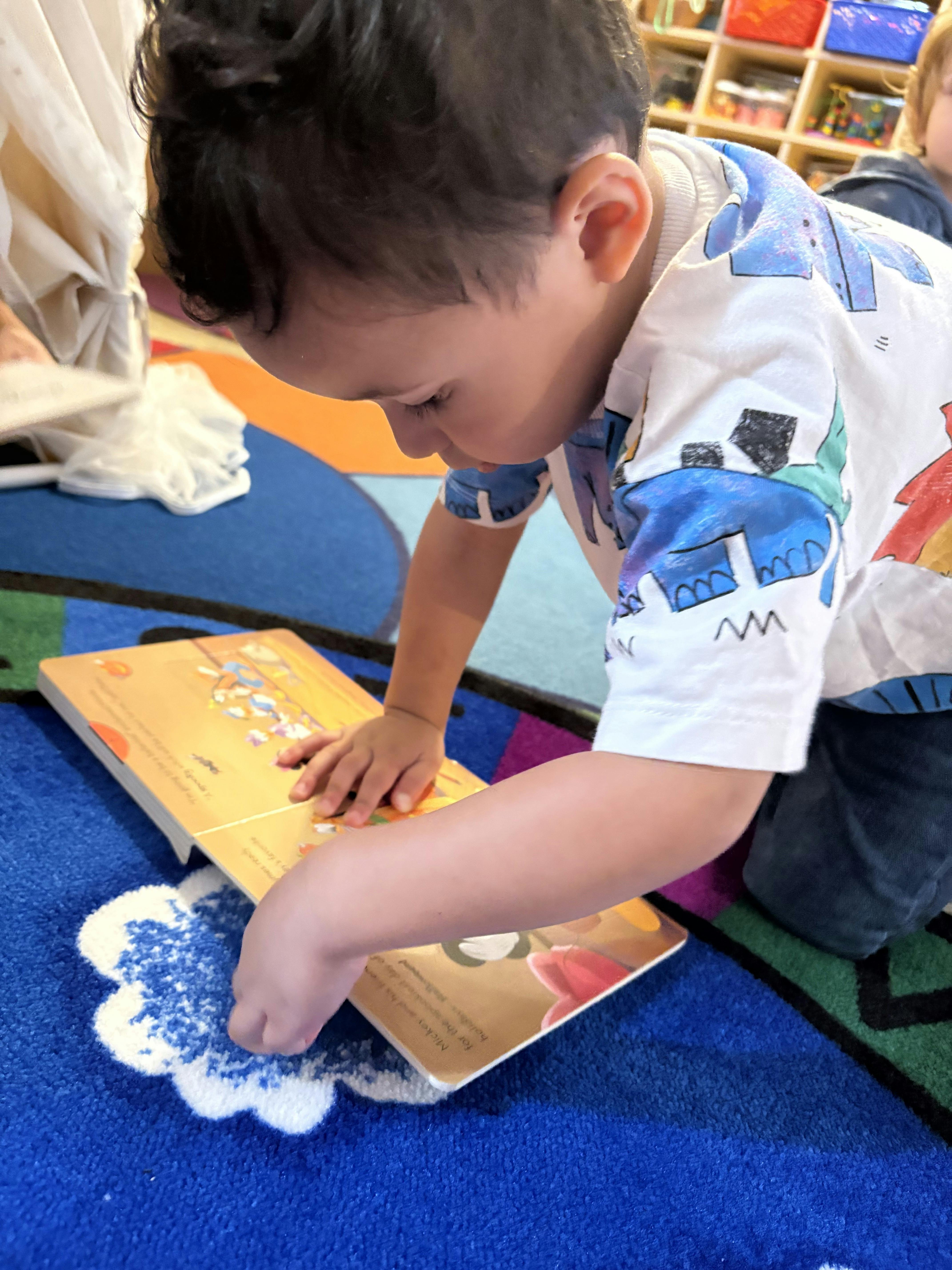 Child on a colorful rug looking at an open book