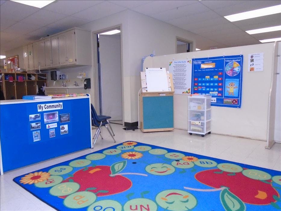 Classroom with a blue rug featuring apples and alphabet letters