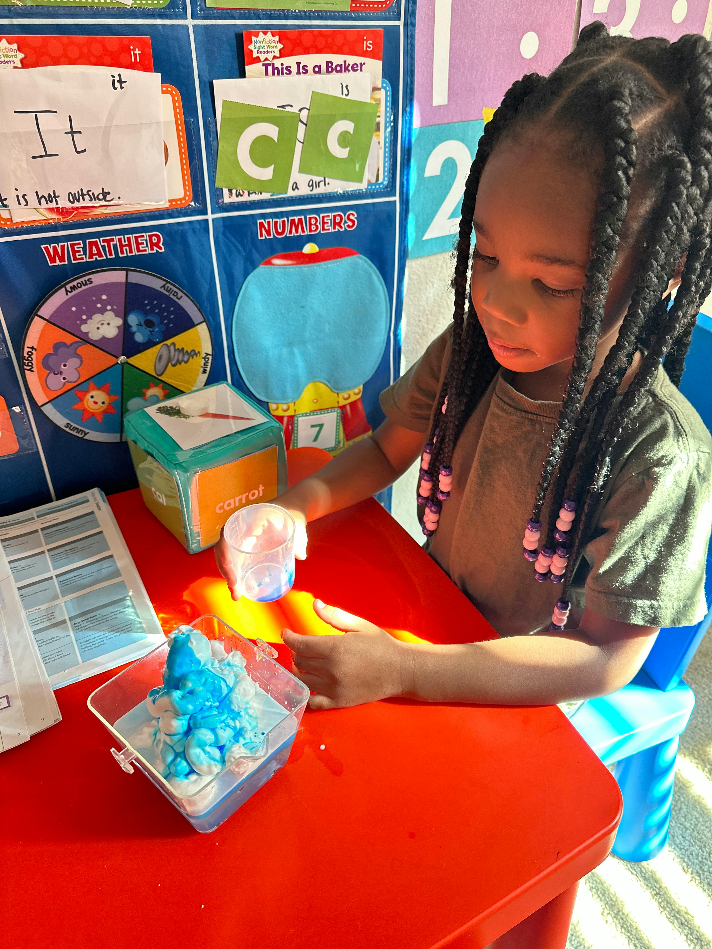 Child at a table with blue and white material in a clear container