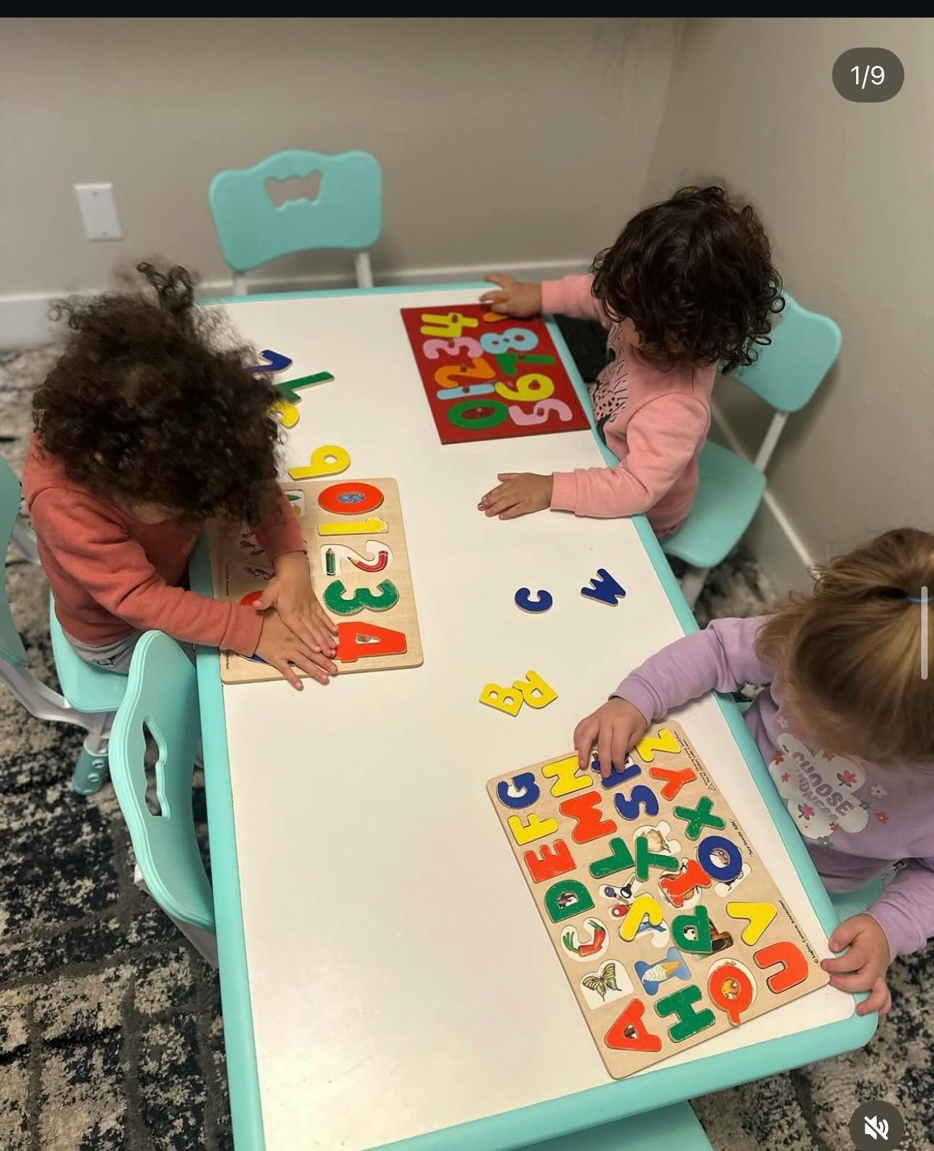 Three children playing with number and letter puzzles at a table