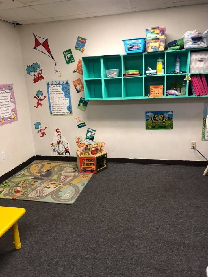 Playroom with teal shelves, wall decals, and a colorful rug