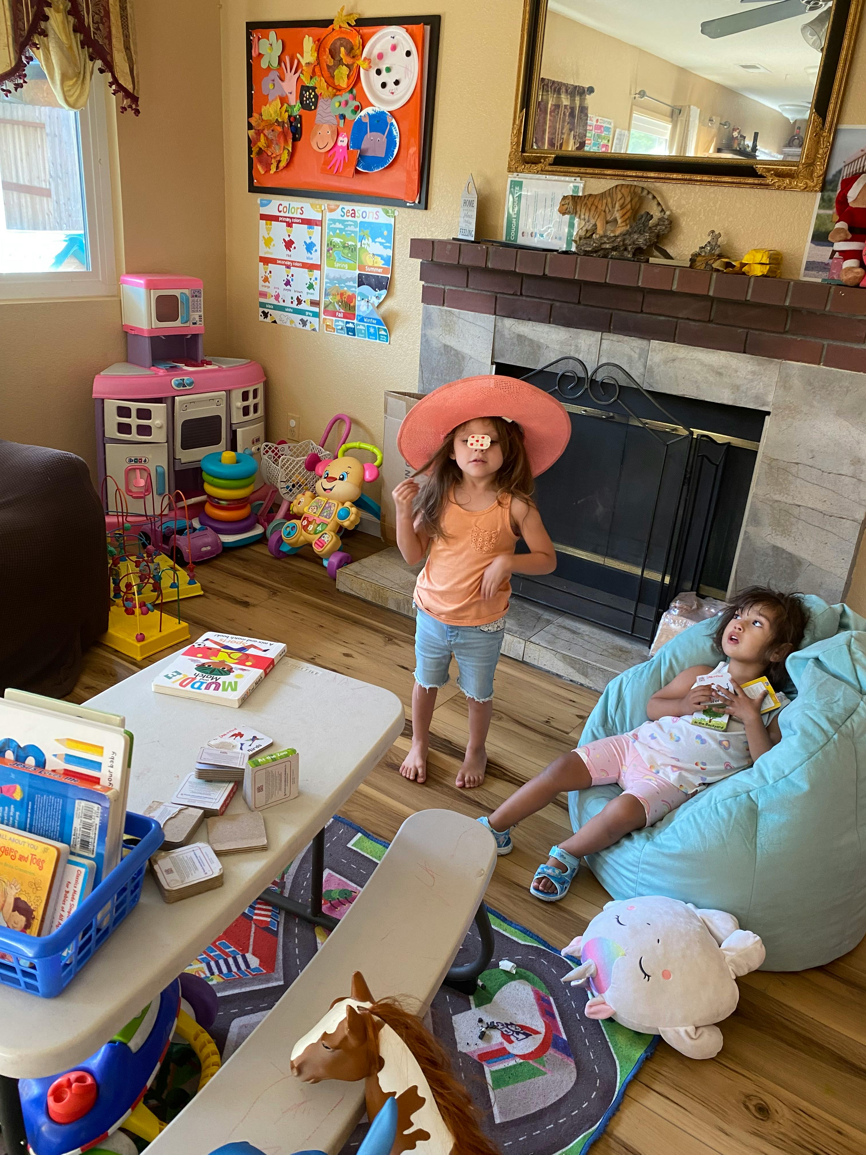 Child in a hat standing, another child sitting in a beanbag chair
