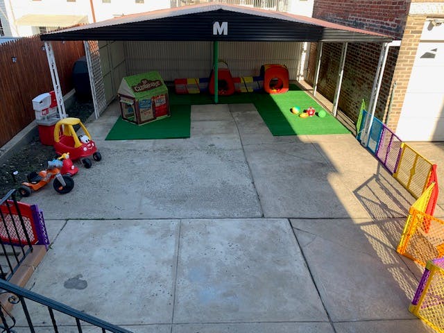 Outdoor play area with toy cars, playhouse, and colorful fence