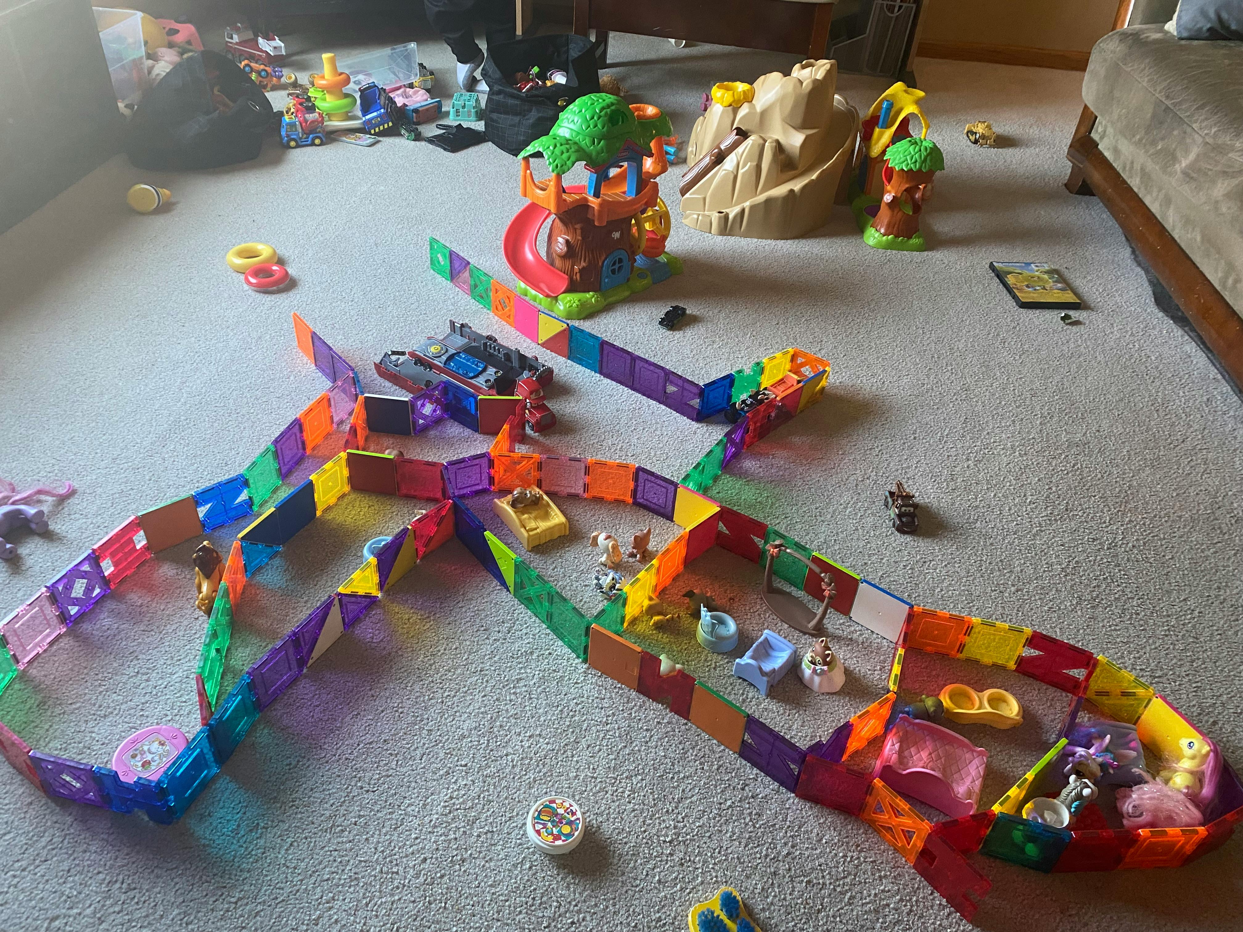 Colorful magnetic tile track with small toys on a carpeted floor